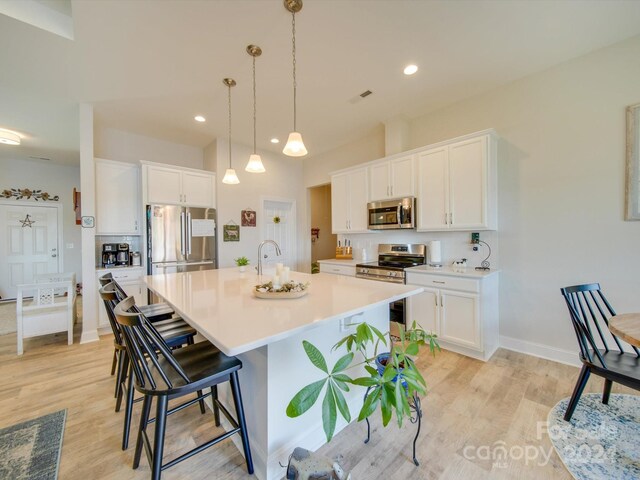 kitchen featuring light wood-type flooring, white cabinetry, a kitchen island with sink, and appliances with stainless steel finishes