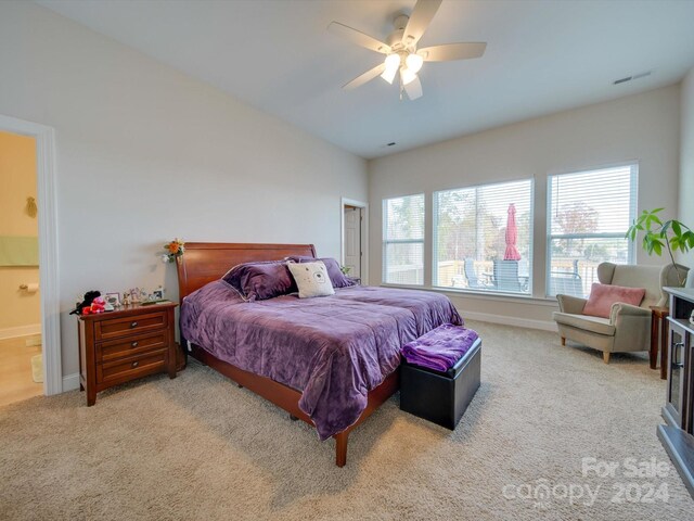 bedroom with ceiling fan, light carpet, connected bathroom, and vaulted ceiling