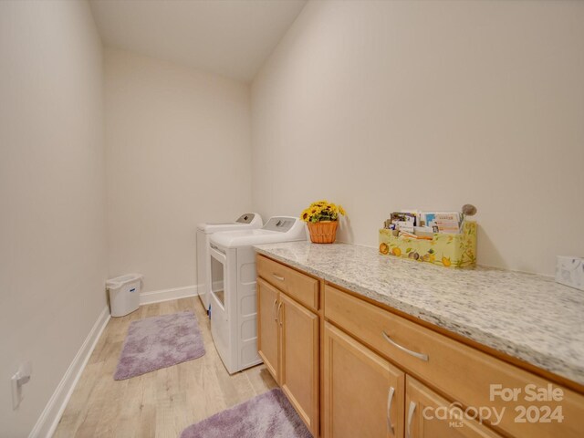 laundry area with cabinets, light hardwood / wood-style flooring, and washer and dryer