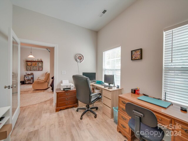 office space featuring french doors, light hardwood / wood-style flooring, and lofted ceiling