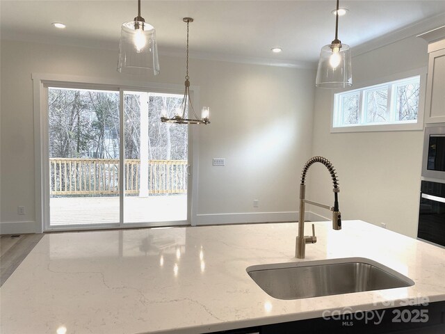 kitchen featuring a wealth of natural light, ornamental molding, a sink, and oven