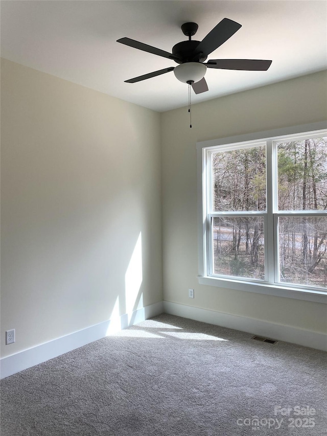 spare room with carpet floors, visible vents, ceiling fan, and baseboards