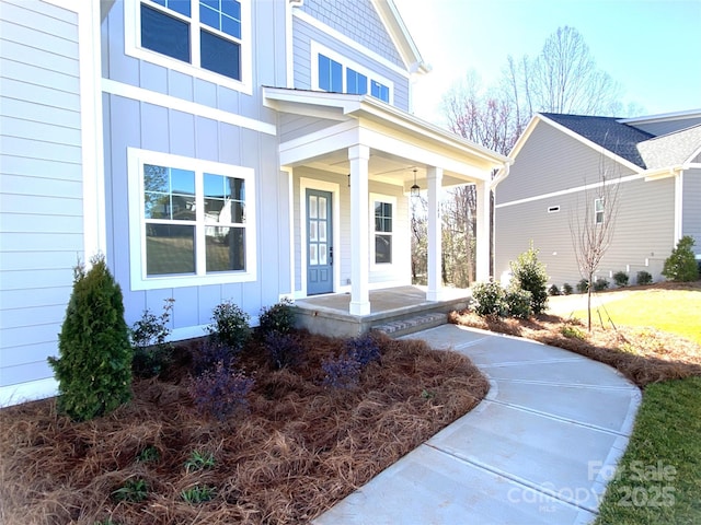 view of exterior entry featuring covered porch and board and batten siding