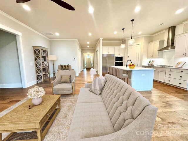 living room featuring ceiling fan, light hardwood / wood-style flooring, and ornamental molding