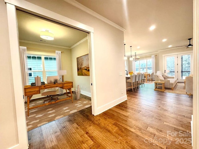 hall featuring a chandelier, hardwood / wood-style floors, and crown molding