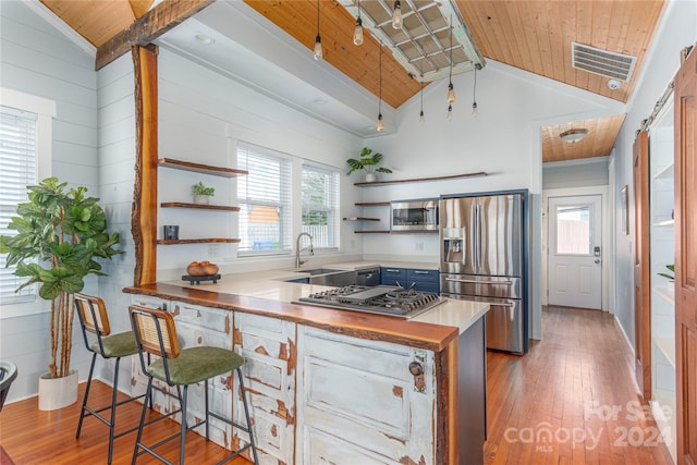 kitchen with a kitchen bar, stainless steel appliances, sink, wooden ceiling, and lofted ceiling