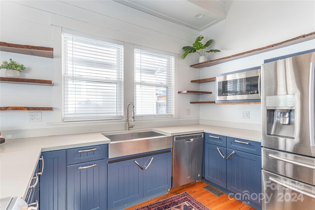 kitchen featuring blue cabinetry, stainless steel appliances, light hardwood / wood-style floors, and sink