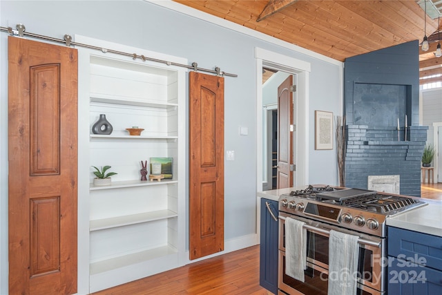 kitchen with hardwood / wood-style floors, a barn door, stainless steel stove, and wood ceiling