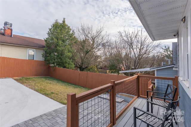 wooden terrace featuring a lawn and a patio area