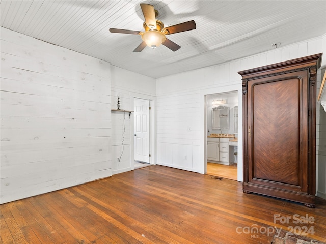 empty room featuring dark hardwood / wood-style floors, wood walls, and ceiling fan