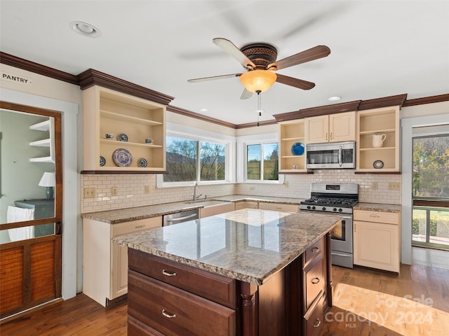 kitchen with appliances with stainless steel finishes, light hardwood / wood-style flooring, a wealth of natural light, and light stone counters