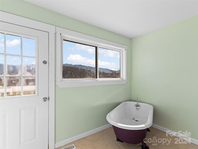 bathroom with a tub to relax in, a mountain view, plenty of natural light, and tile patterned floors