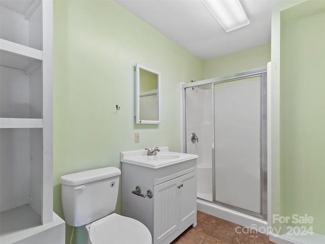 bathroom featuring vanity, toilet, and a shower with door