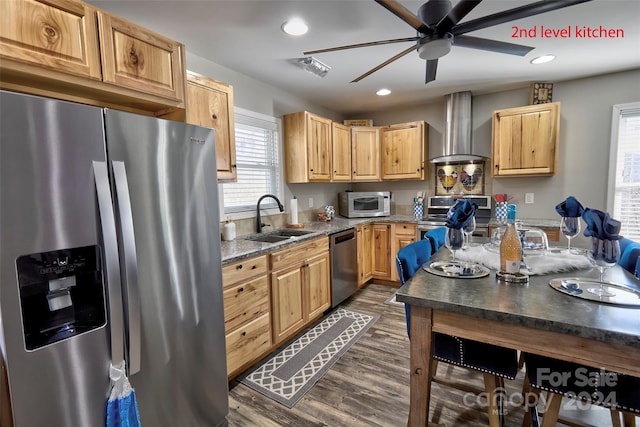 kitchen featuring sink, wall chimney exhaust hood, dark hardwood / wood-style floors, ceiling fan, and stainless steel appliances