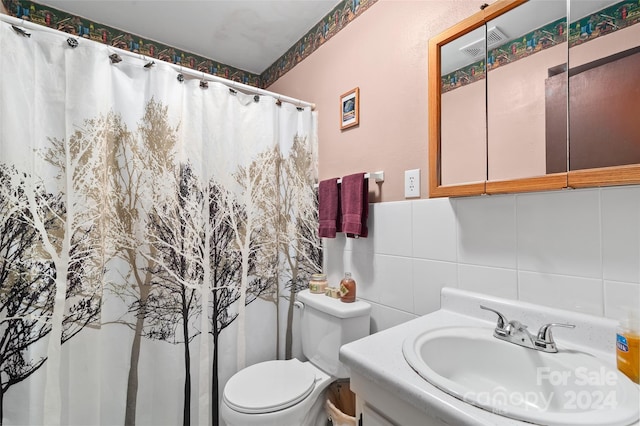 bathroom with decorative backsplash, vanity, toilet, and tile walls