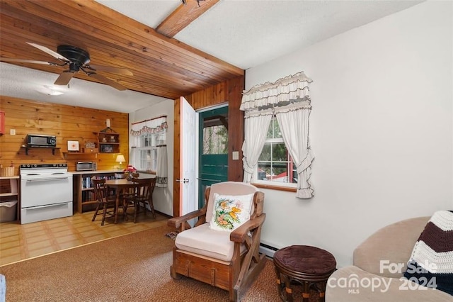 sitting room featuring baseboard heating, wood walls, carpet flooring, and ceiling fan