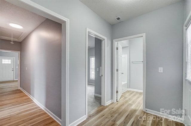 hall featuring a textured ceiling and light wood-type flooring