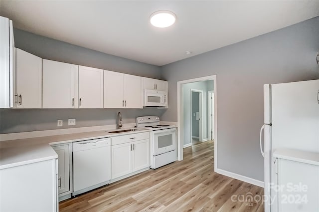 kitchen featuring white cabinetry, sink, light hardwood / wood-style floors, and white appliances