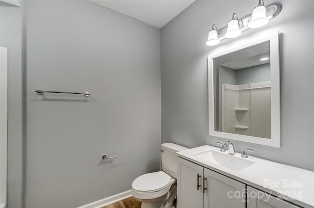 bathroom featuring walk in shower, vanity, wood-type flooring, and toilet