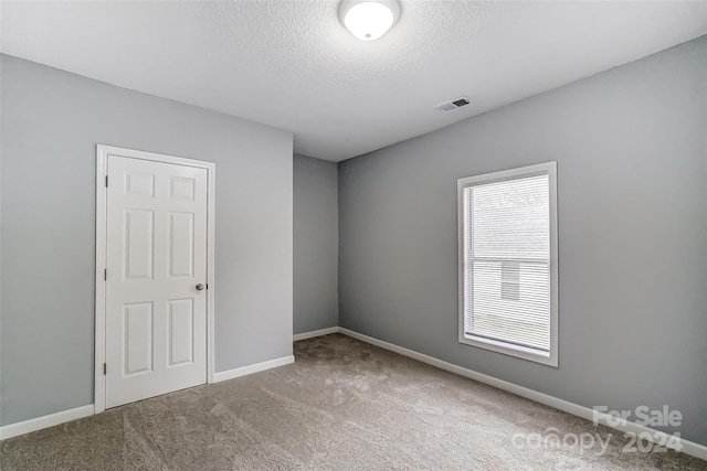 carpeted spare room featuring a textured ceiling