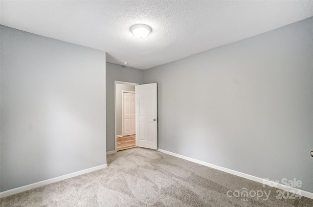 carpeted empty room featuring a textured ceiling