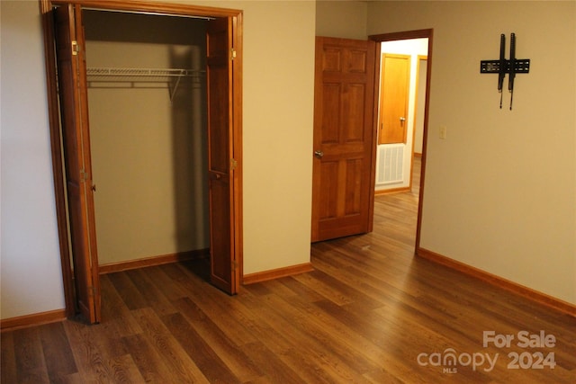 unfurnished bedroom featuring dark wood-type flooring and a closet