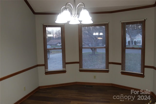 spare room featuring crown molding, dark hardwood / wood-style flooring, and a chandelier