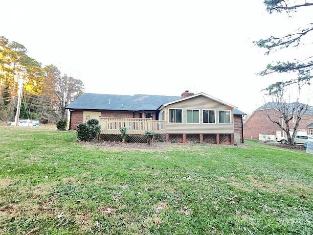 back of property with a wooden deck and a lawn