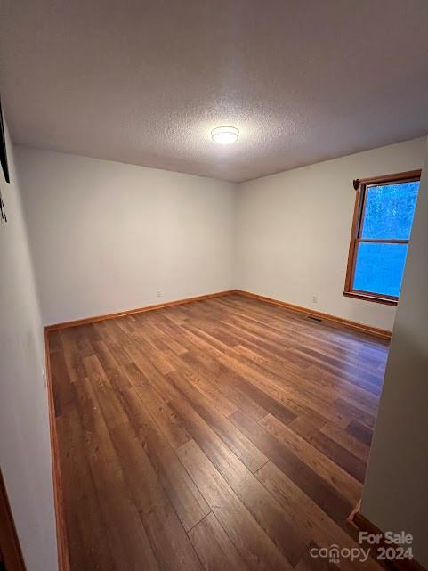 unfurnished room with a textured ceiling and hardwood / wood-style flooring