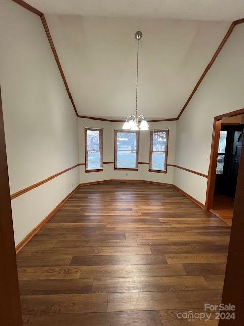 unfurnished dining area with a chandelier, dark hardwood / wood-style floors, vaulted ceiling, and a healthy amount of sunlight