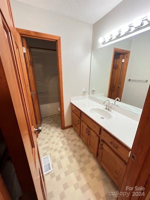 full bathroom featuring vanity, shower / bathtub combination, toilet, and a textured ceiling