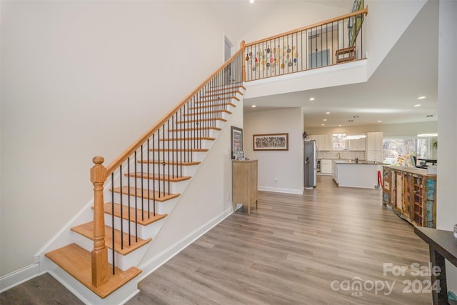 stairs featuring hardwood / wood-style floors and a high ceiling