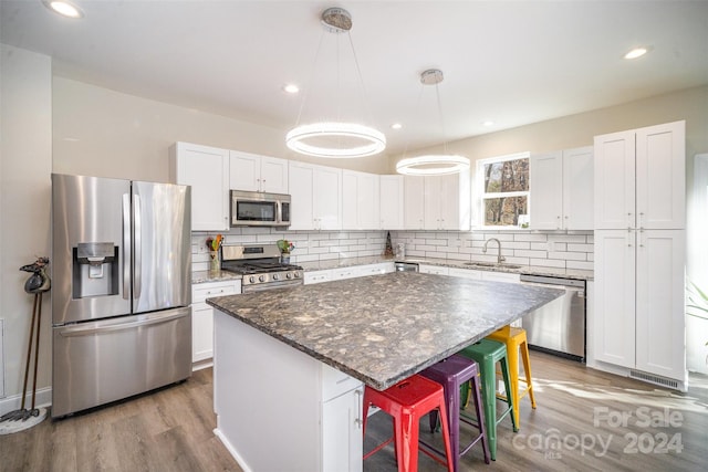 kitchen featuring white cabinetry, a center island, sink, stainless steel appliances, and a breakfast bar area