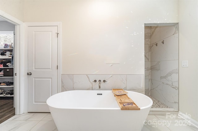 bathroom with tile walls and independent shower and bath