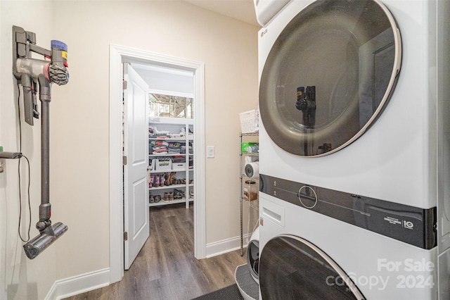 washroom featuring hardwood / wood-style flooring and stacked washer / dryer