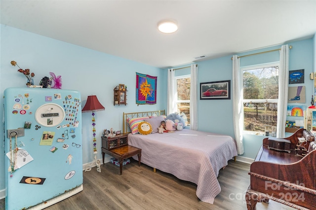 bedroom with hardwood / wood-style flooring and refrigerator