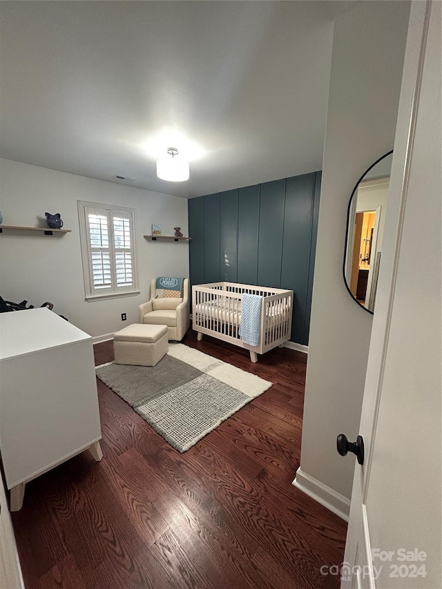 bedroom featuring a crib and dark wood-type flooring