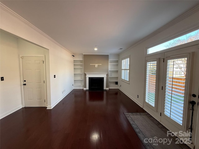 unfurnished living room featuring built in features, dark wood finished floors, baseboards, a fireplace with flush hearth, and ornamental molding