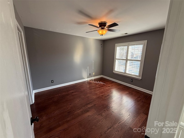 unfurnished room with a ceiling fan, dark wood finished floors, visible vents, and baseboards