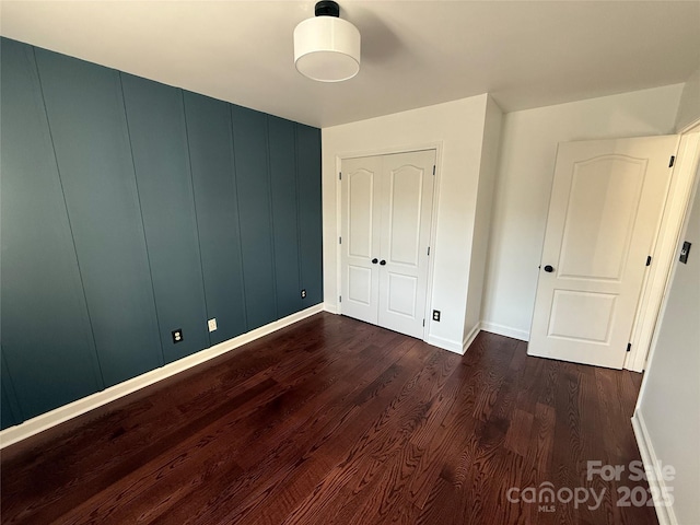 unfurnished bedroom featuring dark wood-style flooring and baseboards