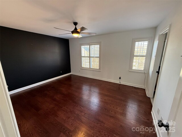 spare room featuring dark wood-type flooring, plenty of natural light, and baseboards