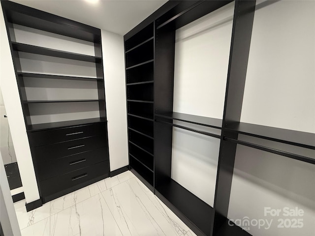 walk in closet featuring marble finish floor