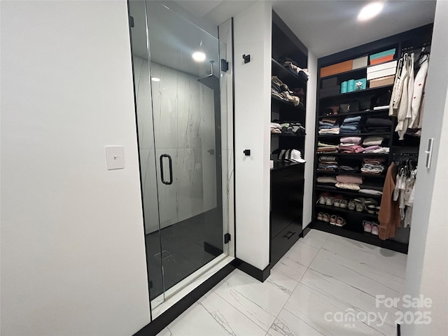 bathroom with marble finish floor, a marble finish shower, and a walk in closet