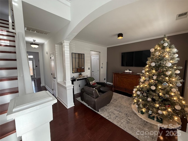 foyer entrance with crown molding, wood finished floors, visible vents, and ornate columns