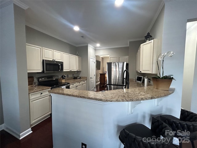 kitchen with appliances with stainless steel finishes, a breakfast bar, ornamental molding, and a peninsula