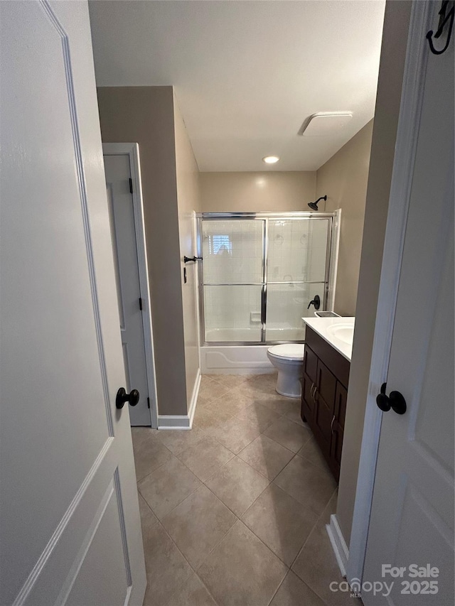 bathroom with baseboards, bath / shower combo with glass door, toilet, tile patterned floors, and vanity