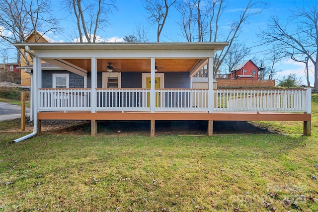 back of house featuring ceiling fan, a wooden deck, and a lawn