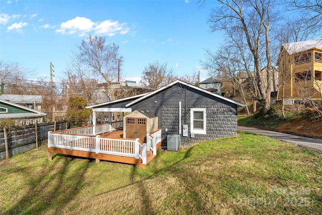 rear view of property featuring a lawn, cooling unit, and a deck