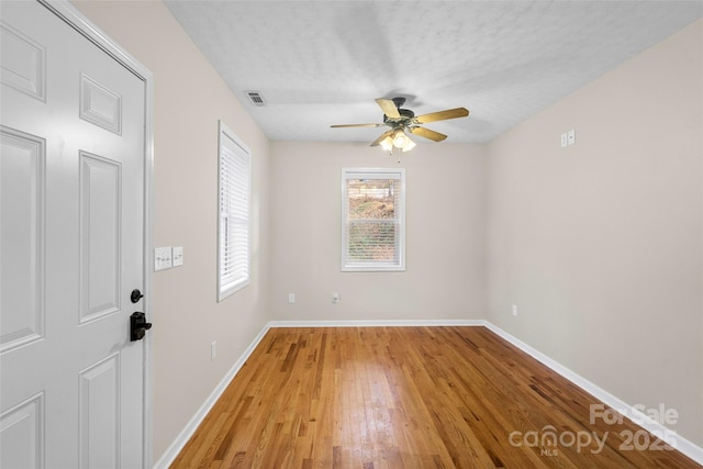 spare room featuring ceiling fan, light wood-type flooring, and a textured ceiling