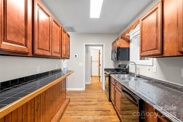 kitchen featuring sink, black appliances, and light wood-type flooring